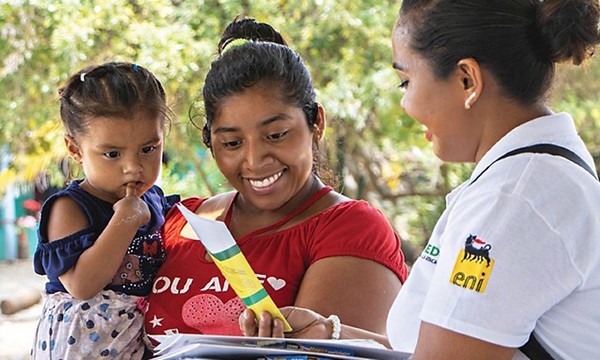 Donna messicana consegna opuscolo informativo a donna messicana con bambino