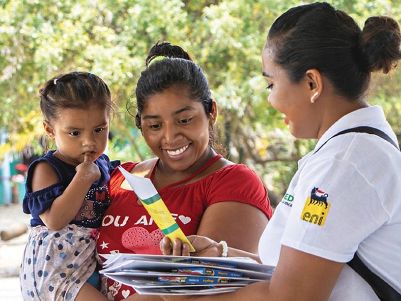 Mexican woman hands out information leaflet to Mexican woman with child