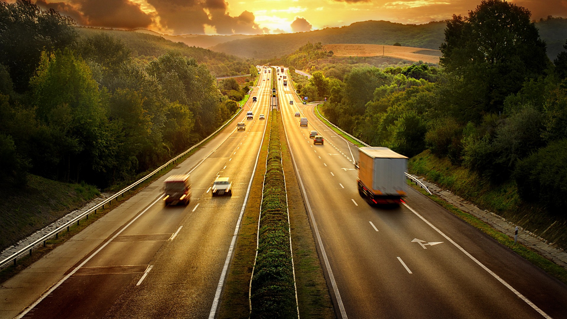 vista di un autostrada al tramonto con automobili e autoarticolati 