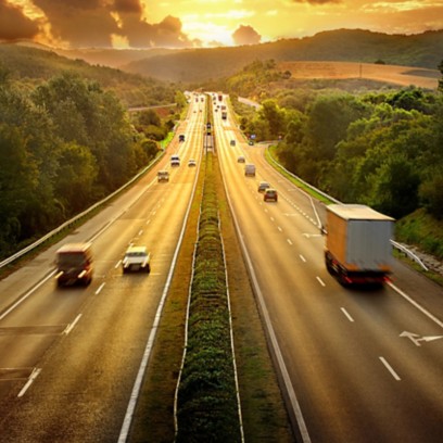 View of a highway at sunset with cars and tractor-trailers 