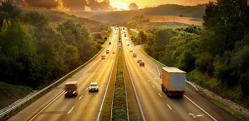 View of a highway at sunset with cars and tractor-trailers 