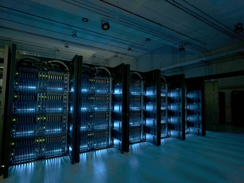 Server racks of a supercomputer in a computing facility, illuminated by blue lights.