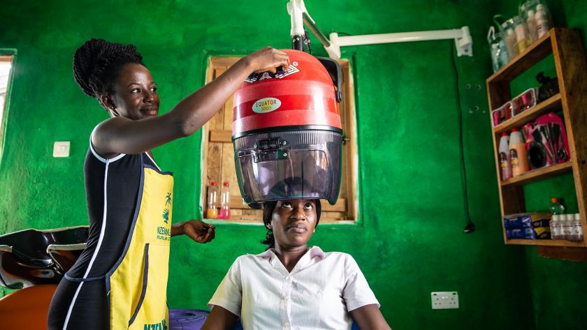 Parrucchiera africana mette casco per asciugare i capelli ad una cliente