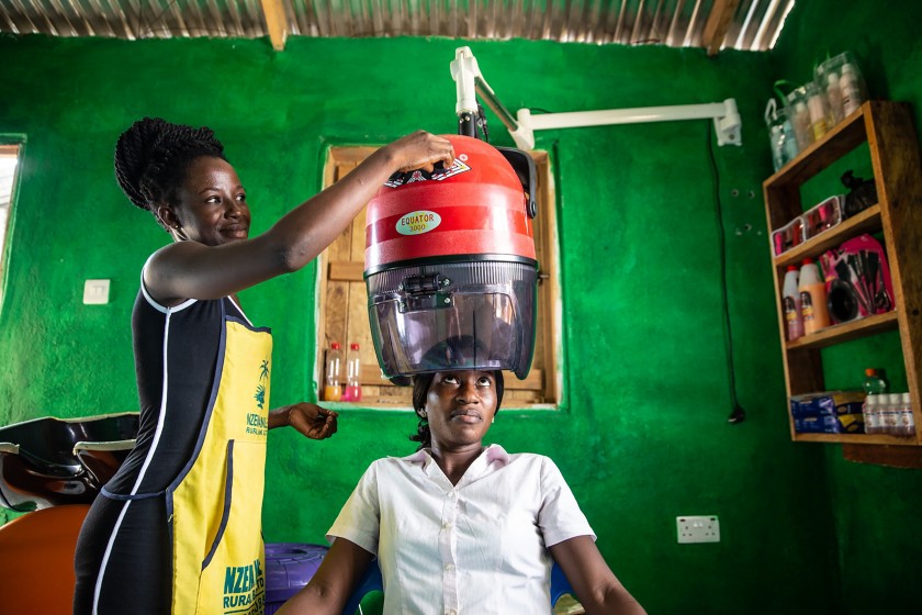 Parrucchiera africana mette casco per asciugare i capelli ad una cliente