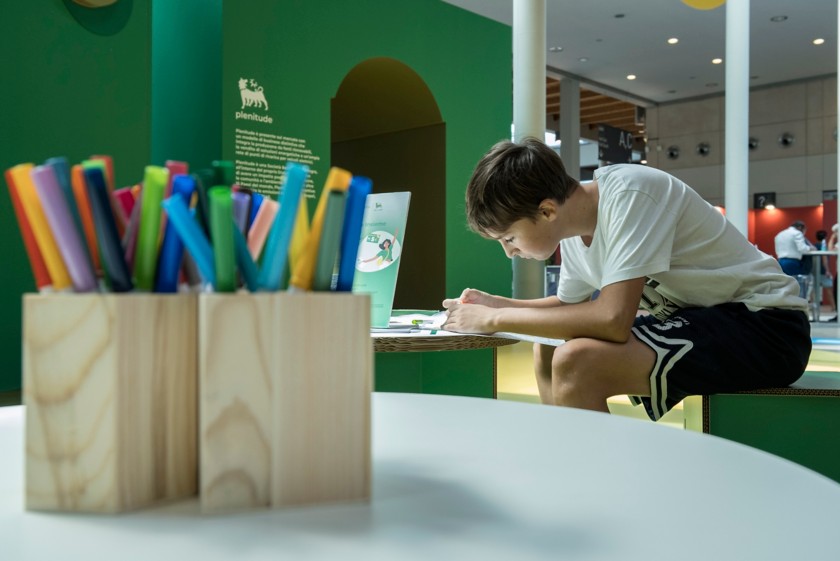 Ragazzino che disegna con i pennarelli, seduto a un tavolo dello stand Eni al Meeting di Rimini