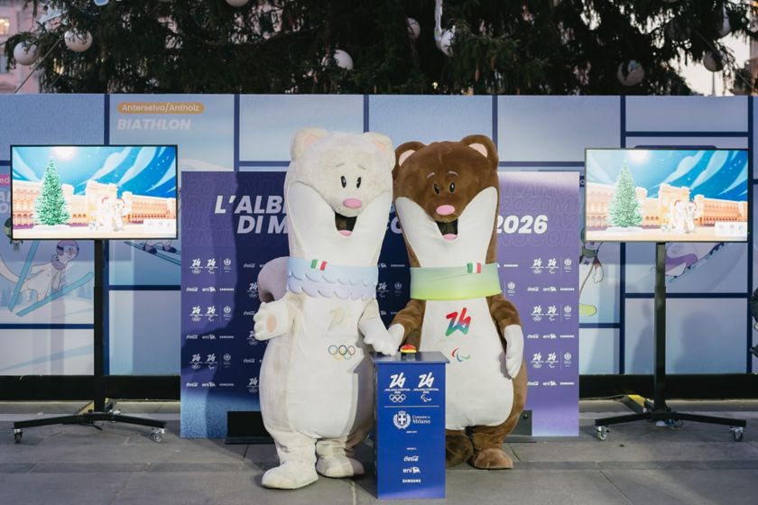 Le Mascotte Tina e Milo con dietro l'Albero dei Giochi di Milano Cortina 2026 in Piazza Duomo a Milano.