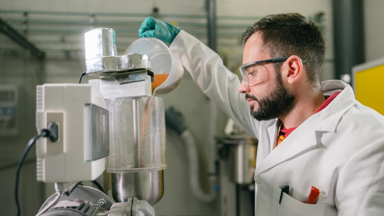 Scientist inserts raw material into machine