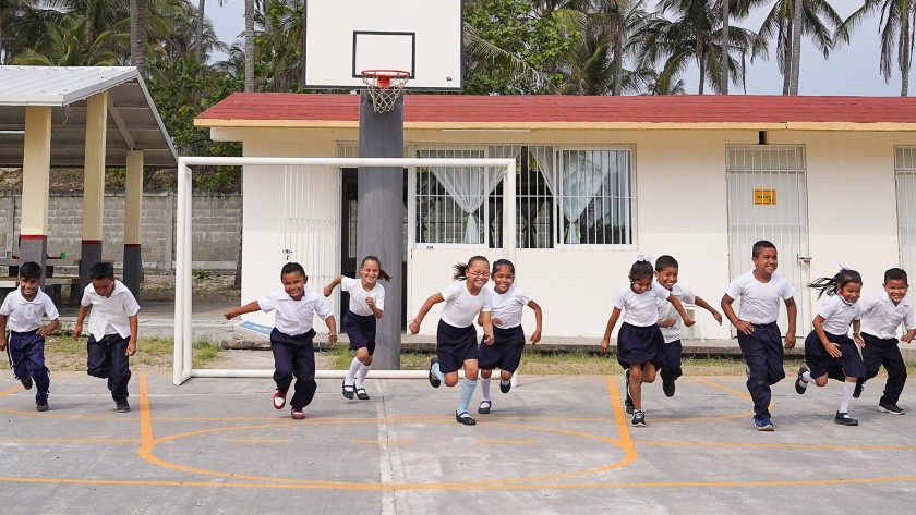 Mexican children sitting in a circle on the floor with the teacher