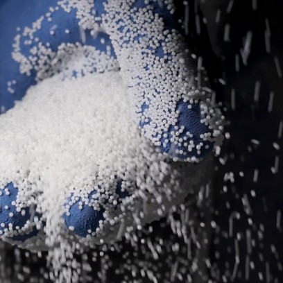 Detail of blue gloved hand holding falling white grains