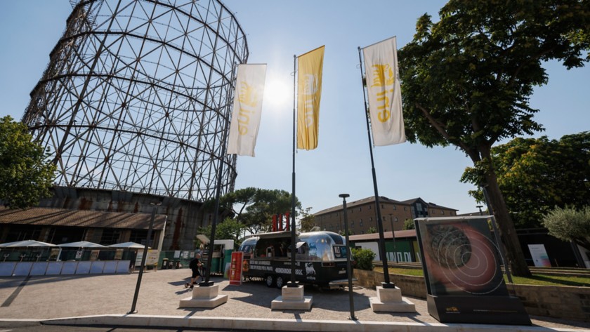 A food truck, Eni flags, and the Gazometro in the background