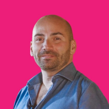 A smiling boy with shaved hair and a blue shirt