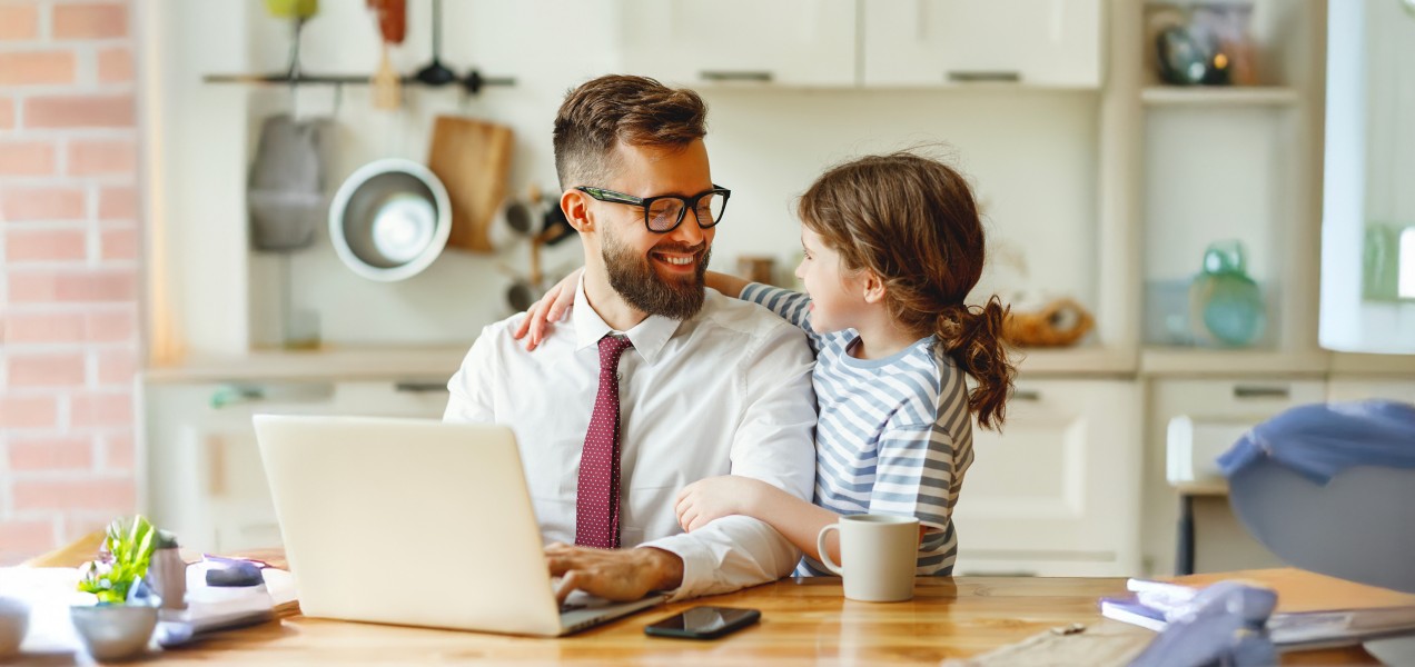uomo seduto al tavolo di fronte al pc con di fianco una bambina