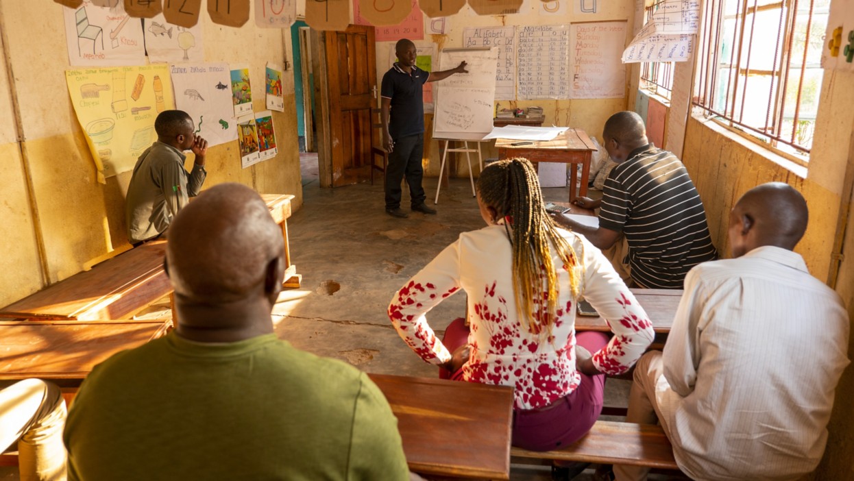 un gruppo di persone in un aula mentre una persona spiega alla lavagna