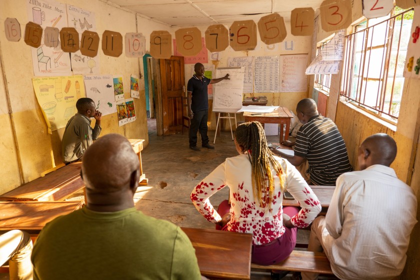 un gruppo di persone in un aula mentre una persona spiega alla lavagna