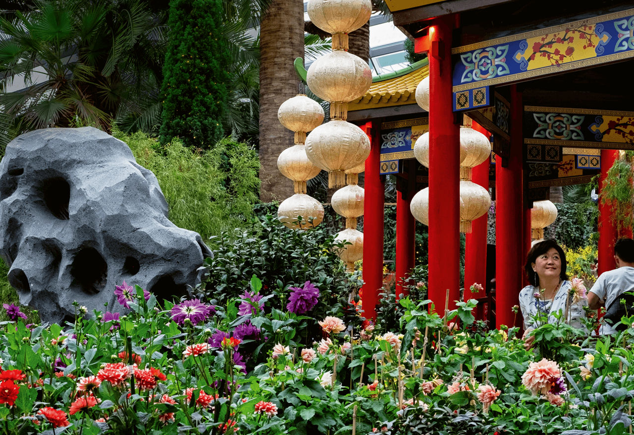 Ein Blumenbeet mit roten Säulen und goldenen Kugeln verziert.