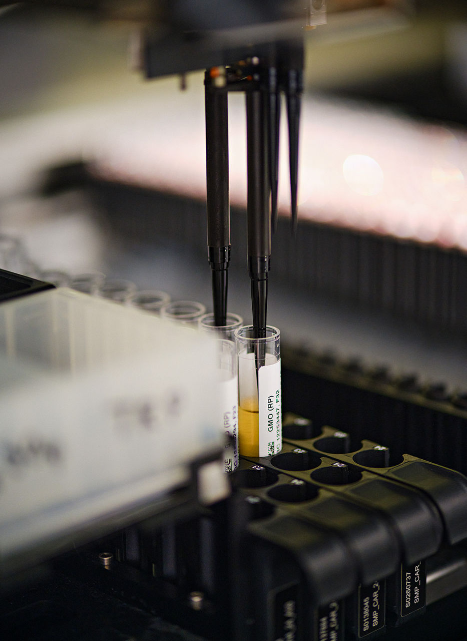 A machine fills yellow liquid into two test tubes in a holder,