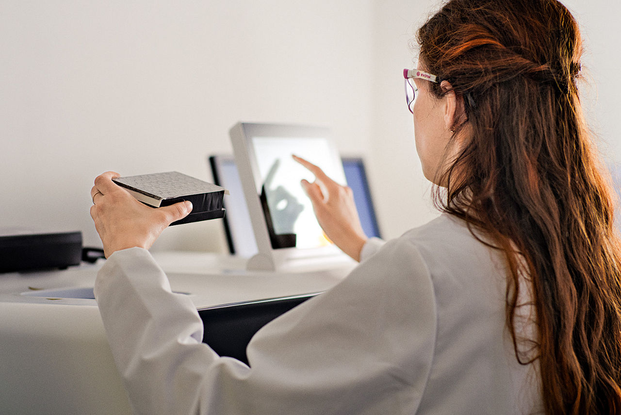 Michelle Dargartz enters data from a display, holding a sample vial in her hand.