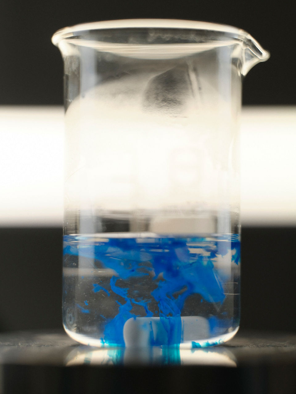 Blue plastic fragments float in a transparent liquid.