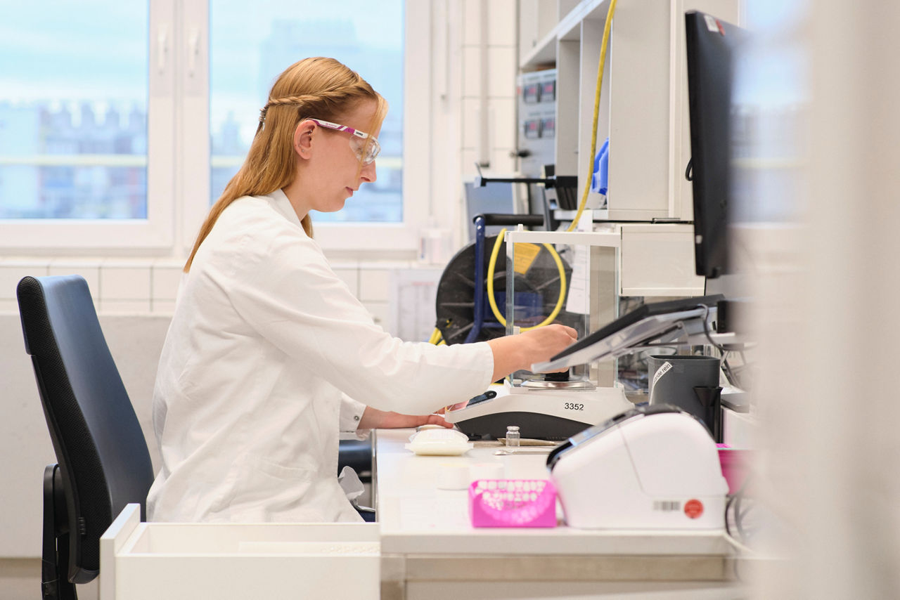 A lab technician sits at a table inspecting products.