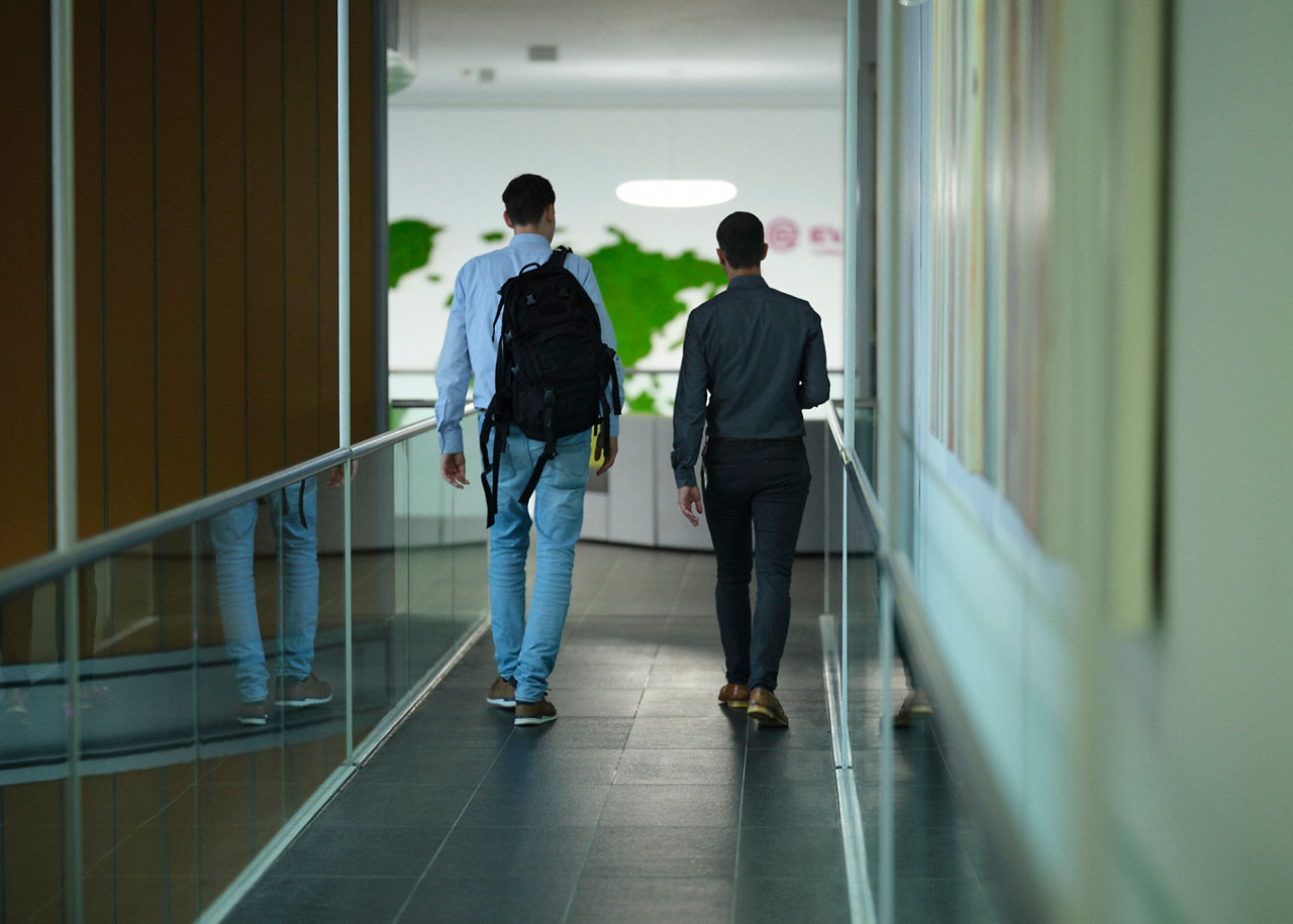 Dürholt and Asche, seen from behind, walk down a long corridor in the Creavis building in Marl., Germany