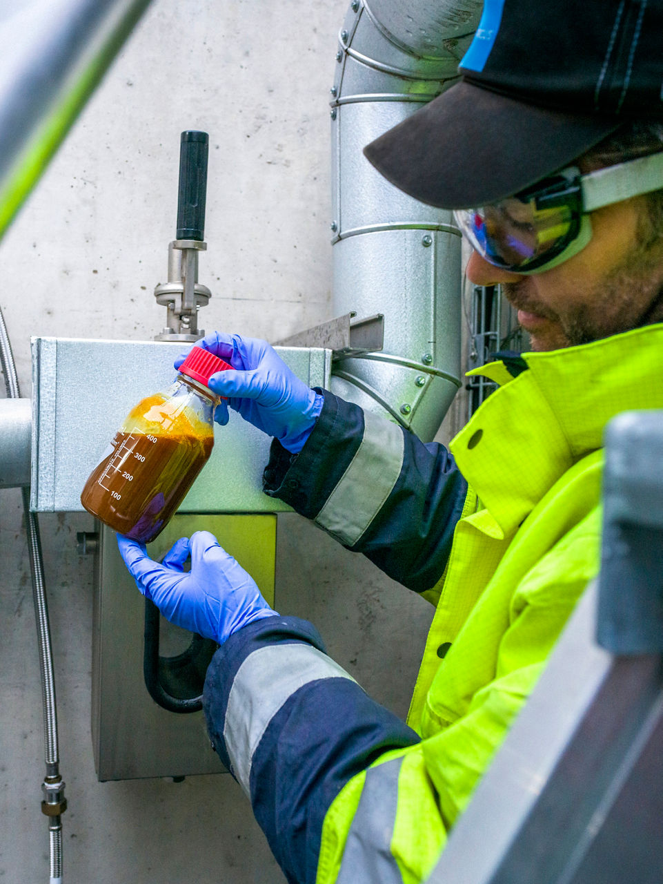 An employee is holding a bottle with a medium-brown liquid in his hands.