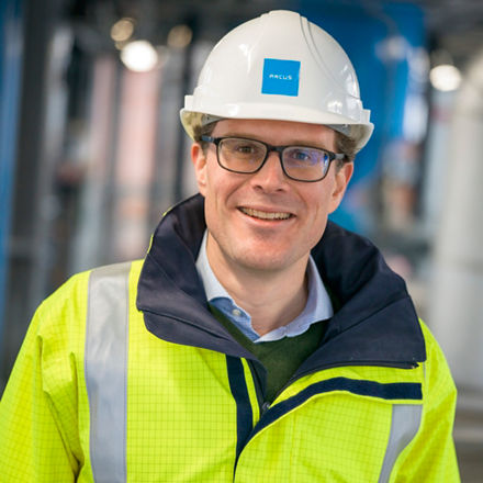 Daniel Odenthal in neongelber Schutzjacke mit Helm auf dem Kopf.