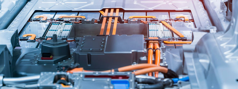 Interior view of an electric vehicle showcasing the battery and high-voltage system with visible orange cables and metallic structure.