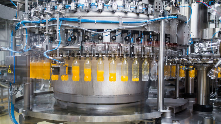 Industrial factory indoors and machinery. Robotic factory line for processing and bottling of soda and orange juice bottles. Selective focus. Short depth of field.