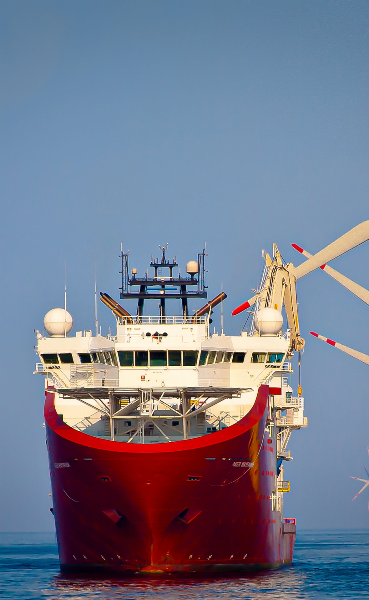 Ein Serviceschiff liegt auf See neben hohen Windkraftanlagen im Bau.