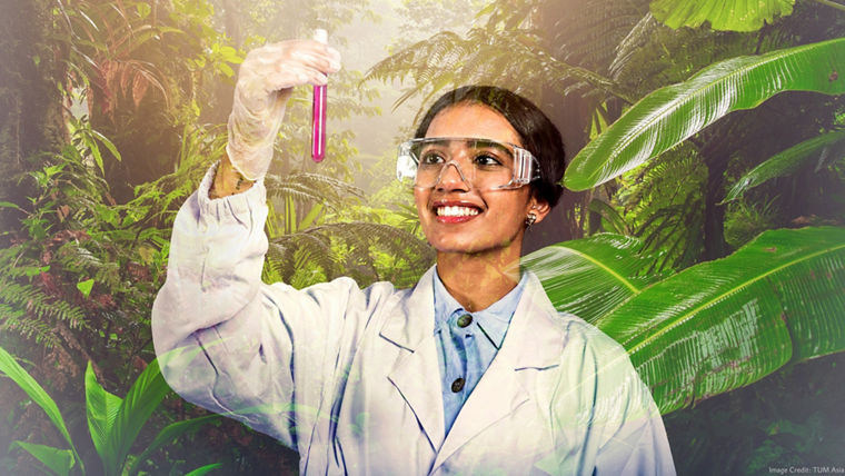 An Evonik employee in a white Evonik lab coat holds a test tube up to the light and looks at it.