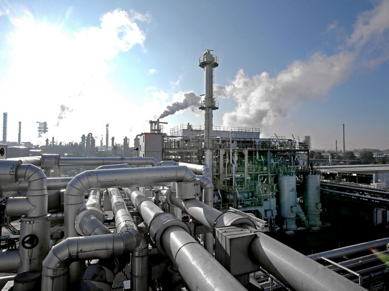 A production facility featuring a tall column and numerous pipe connections.