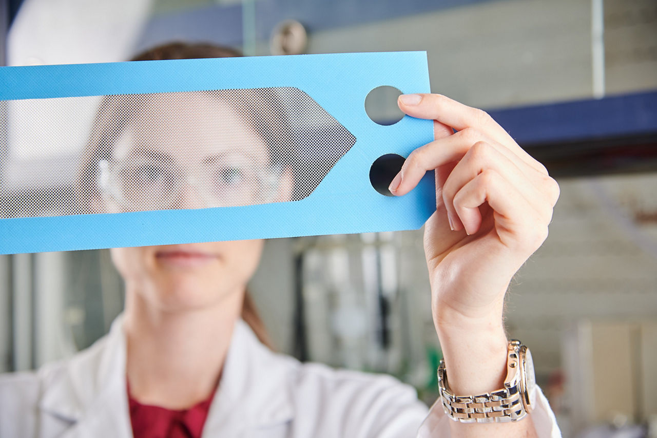 Silvia Blank-Shim looks through a fine mesh structure with a blue rim.