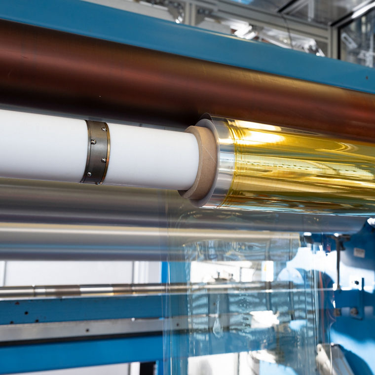 Eine goldglänzende Rolle auf einer weißen Produktionsachse.