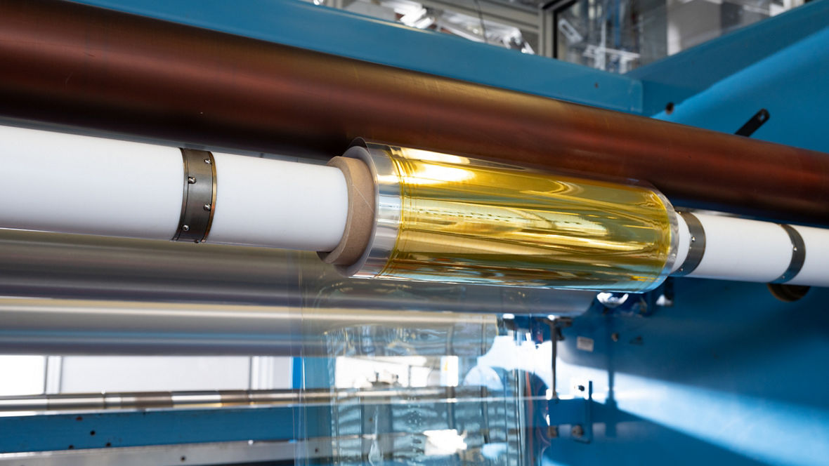 A gold-glimmering roll on a white production axis.