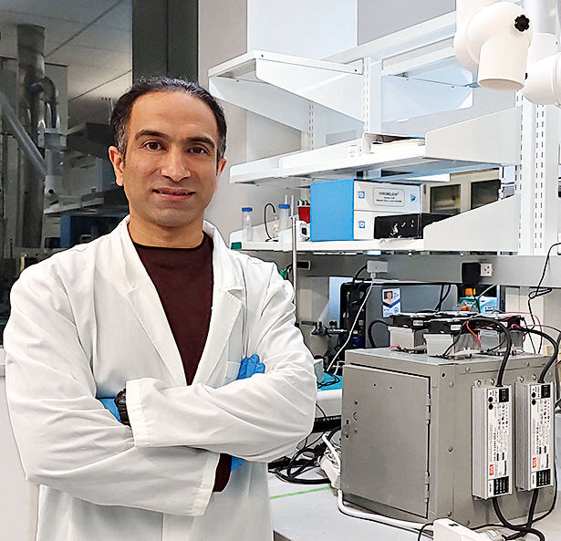 Amin Zadehnazari im Laborkittel neben einer Versuchsanlage