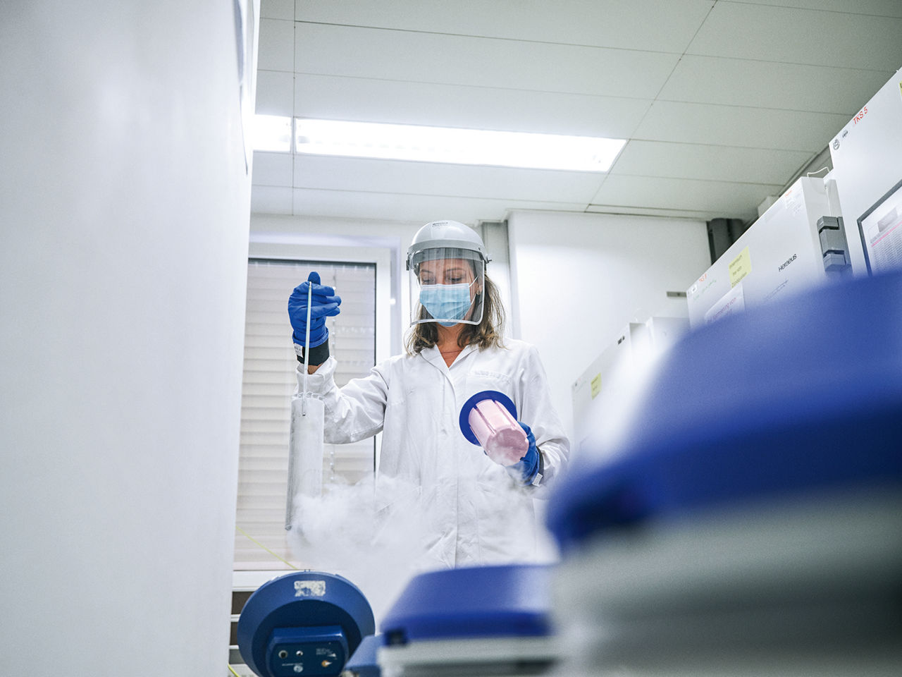 Ein Forscherin mit Gesichtsschutz entnimmt tiefgefrorene Bakterienproben.