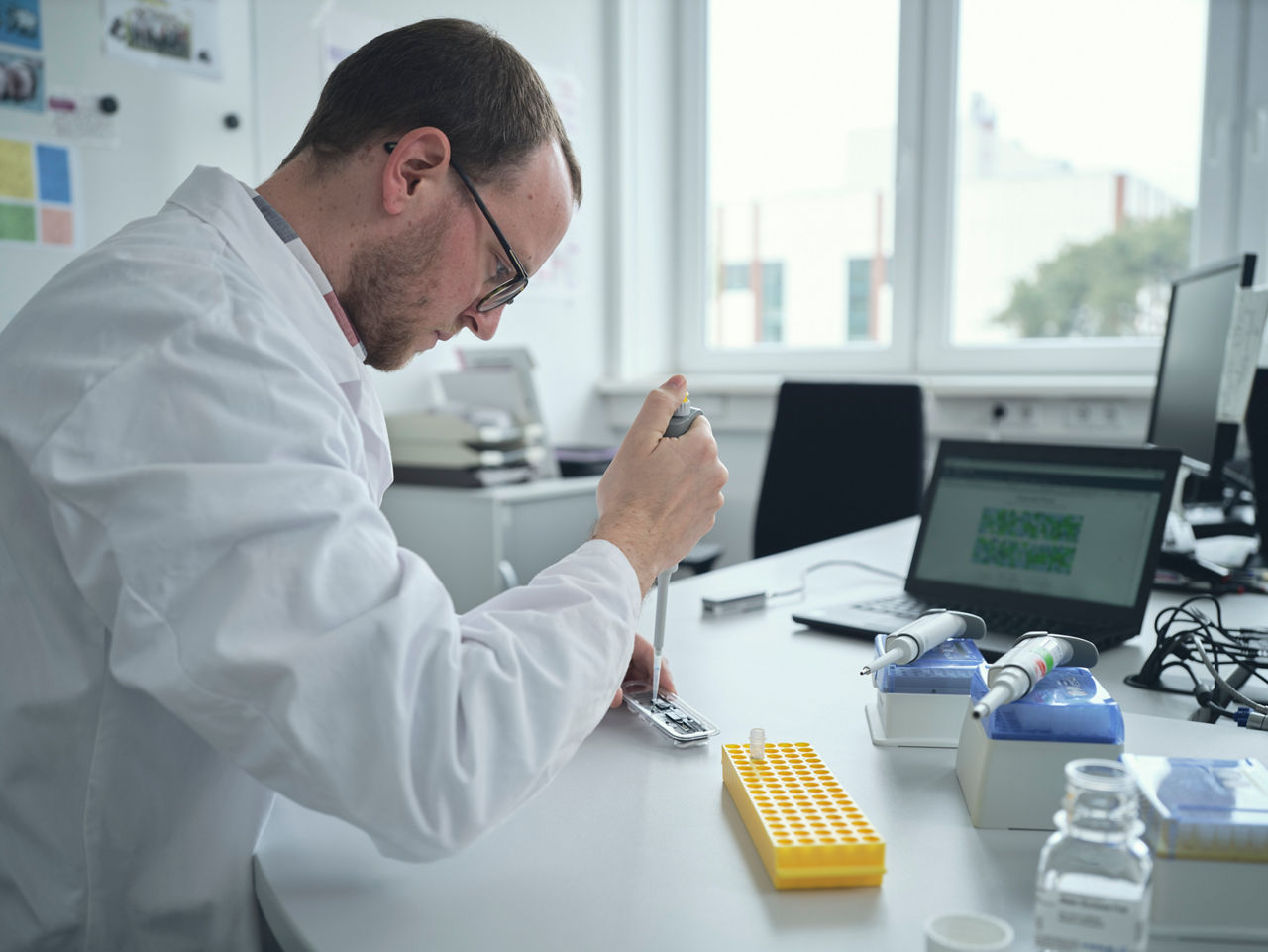 A scientist drips liquid into a small test container.