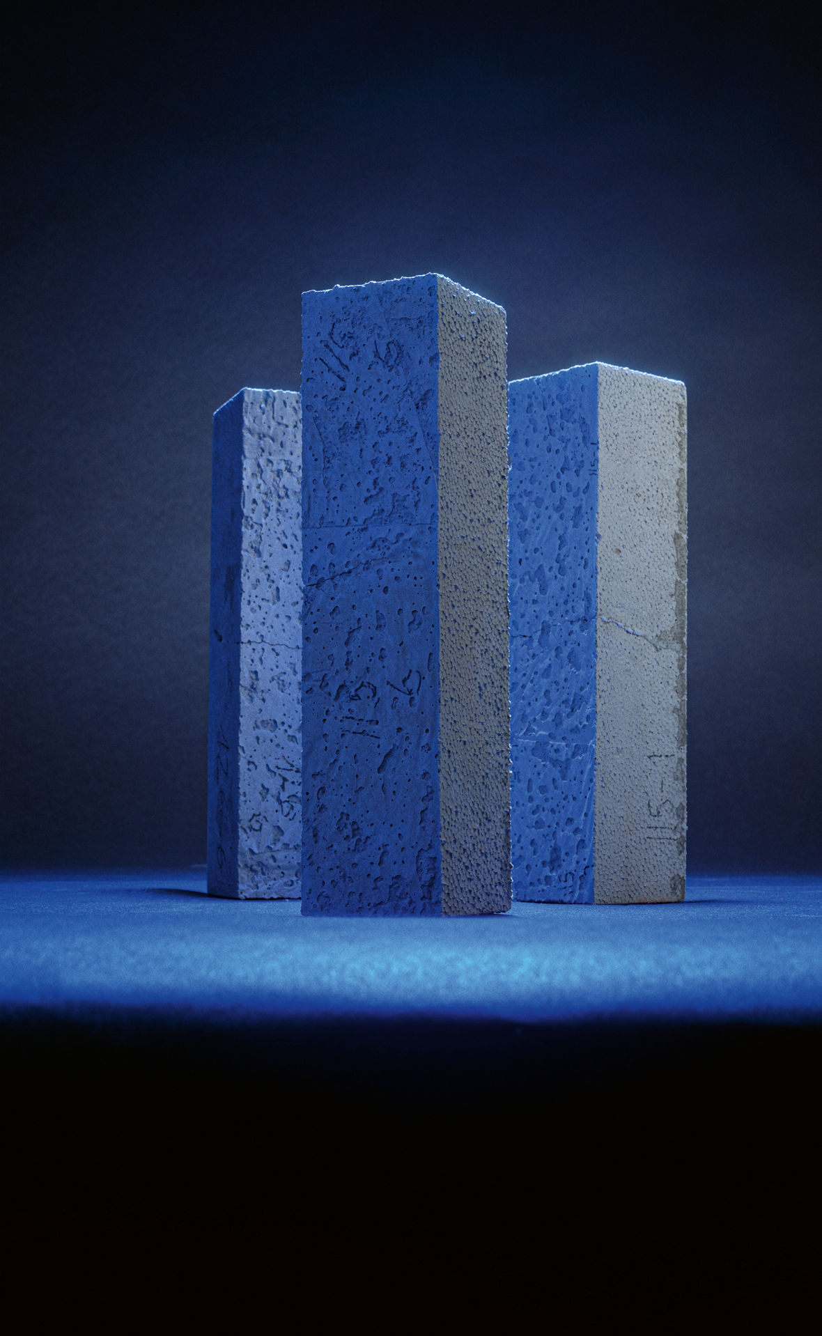 Drei Beton Prüfteile, blau beleuchhtet wie Stelen.