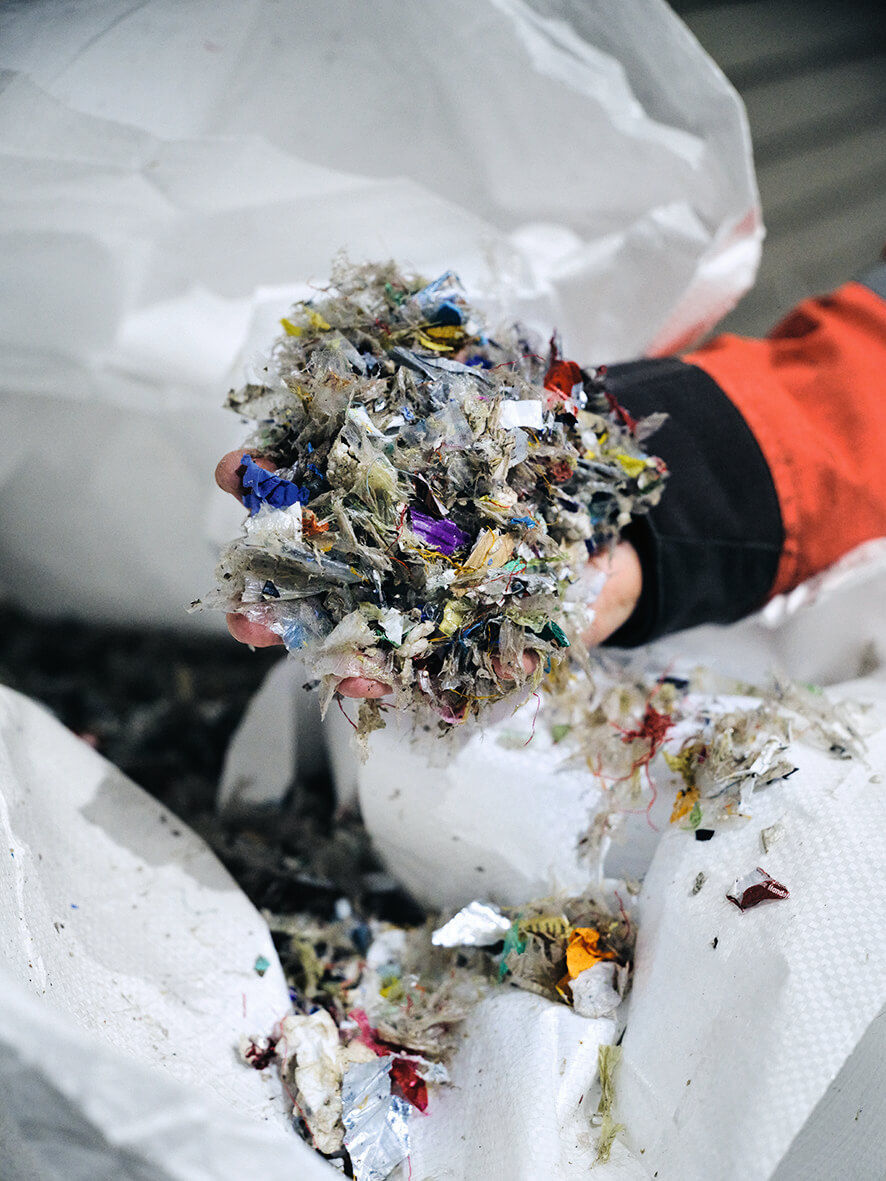 A hand grasps shredded plastic.
