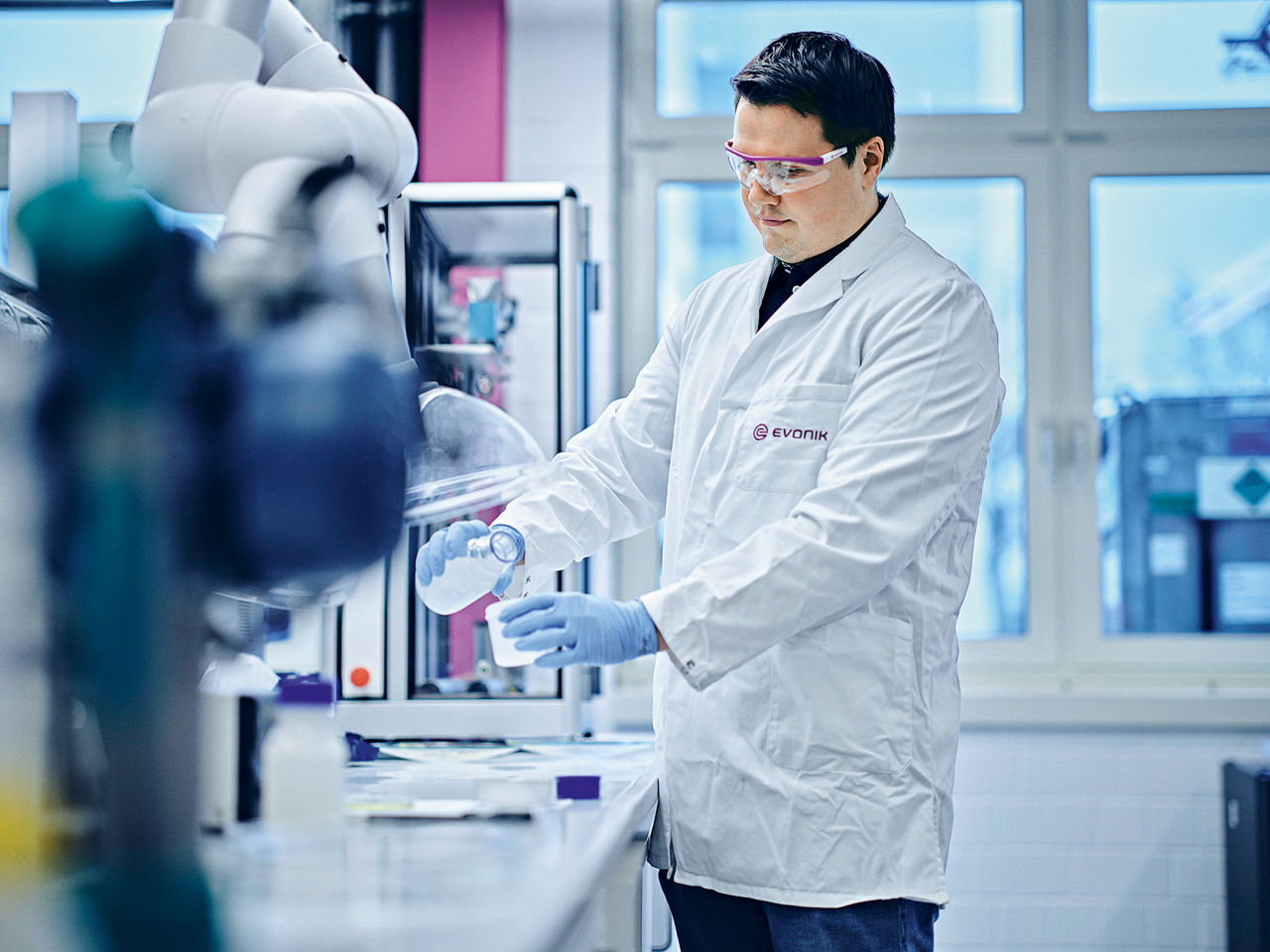 Julian Teichmann schüttet in einem Labor vorsichtig die Flüssigkeit in einen Messbecher.