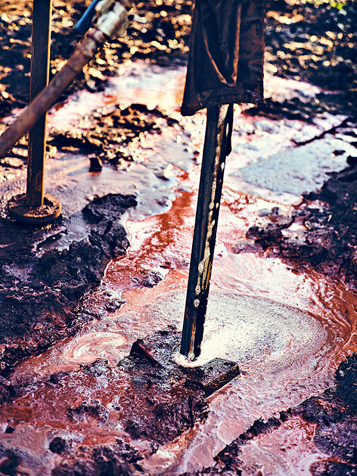 Nahaufnahme des Bohrgestänges, das von rotbrauner Flüssigkeit umspült wird.