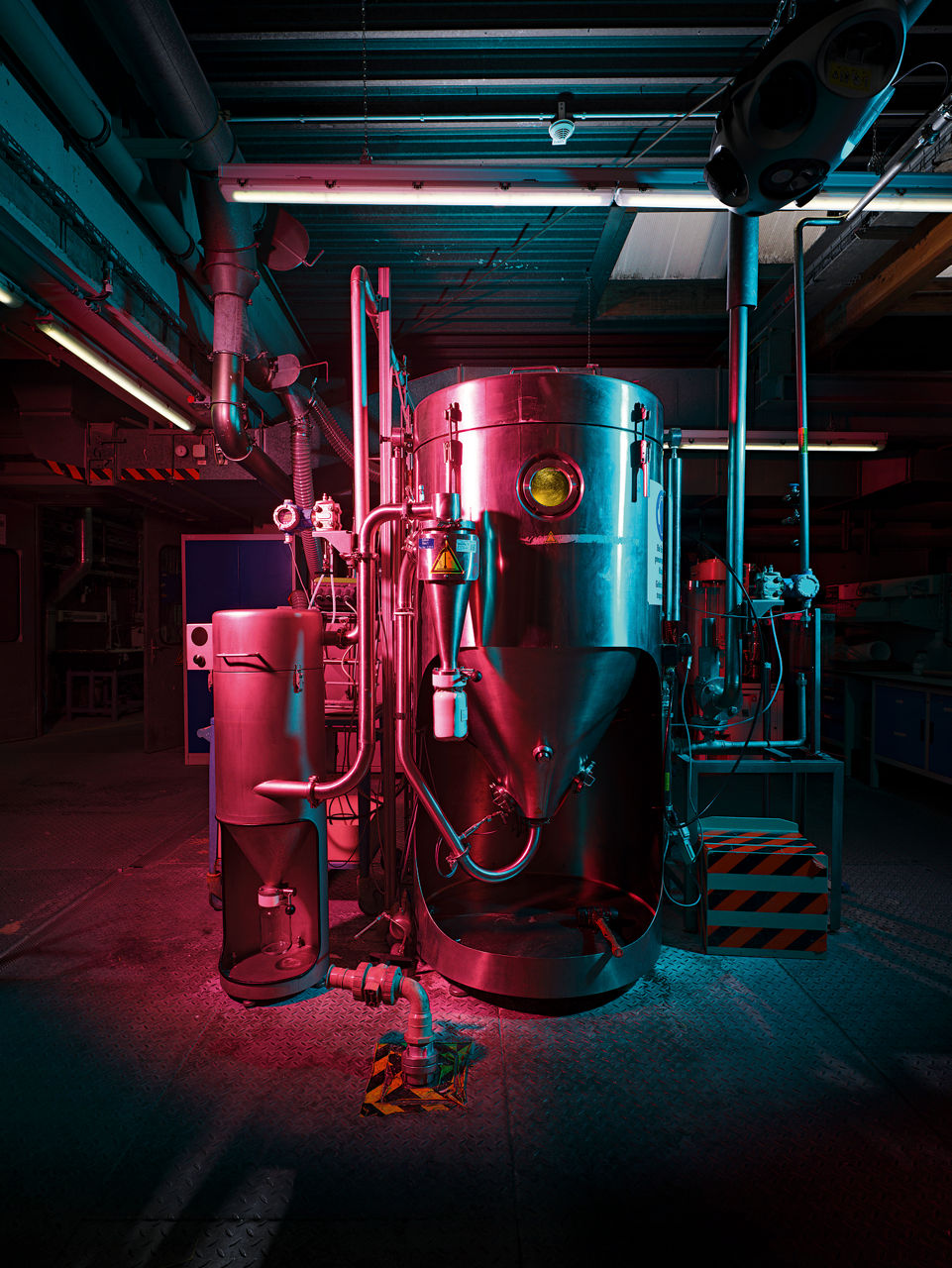 Ein etwa zwei Meter hoher runder Edelstahlbehälter, er wird von links rötlich angeleuchtet.