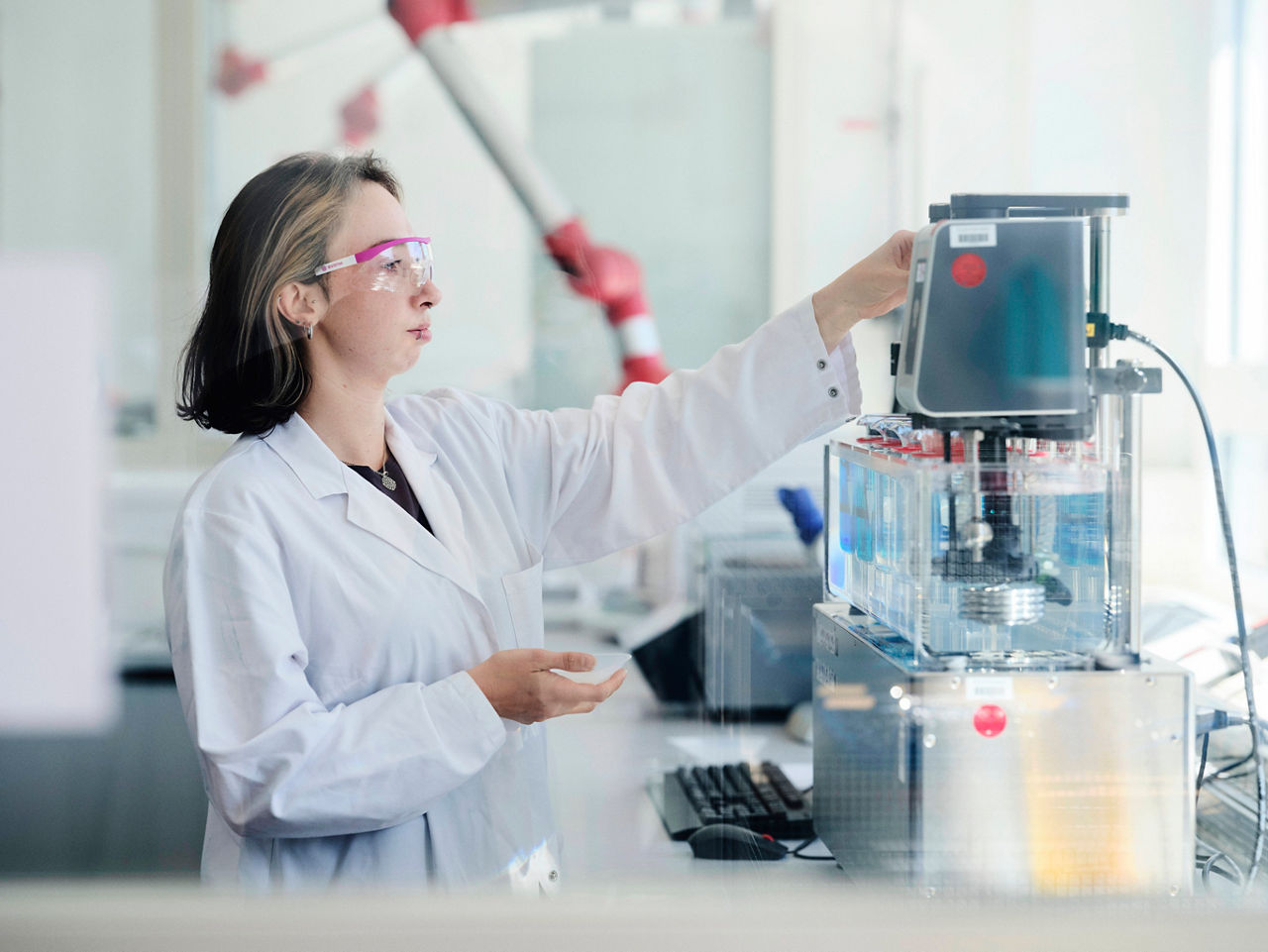 Chemielaborantin Jessica Huppertz füllt Probematerial un einen Behälter, der vor ihr auf einem Labortisch steht.