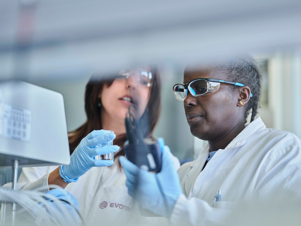 Die beiden Frauen betrachten gemeinsam einen Probenbehälter.