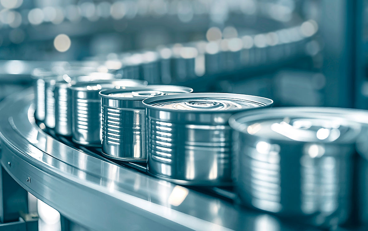 Close-up of silver canned food being processed on a factory production line with aluminum containers, metal conveyor