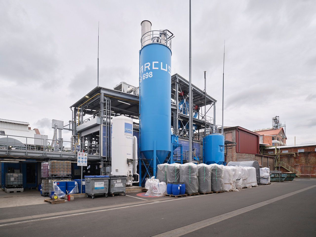 Eine chemische Anlage mit Stahlträgern und zwei blauen Silos, davor Big-Pack-Säcke.