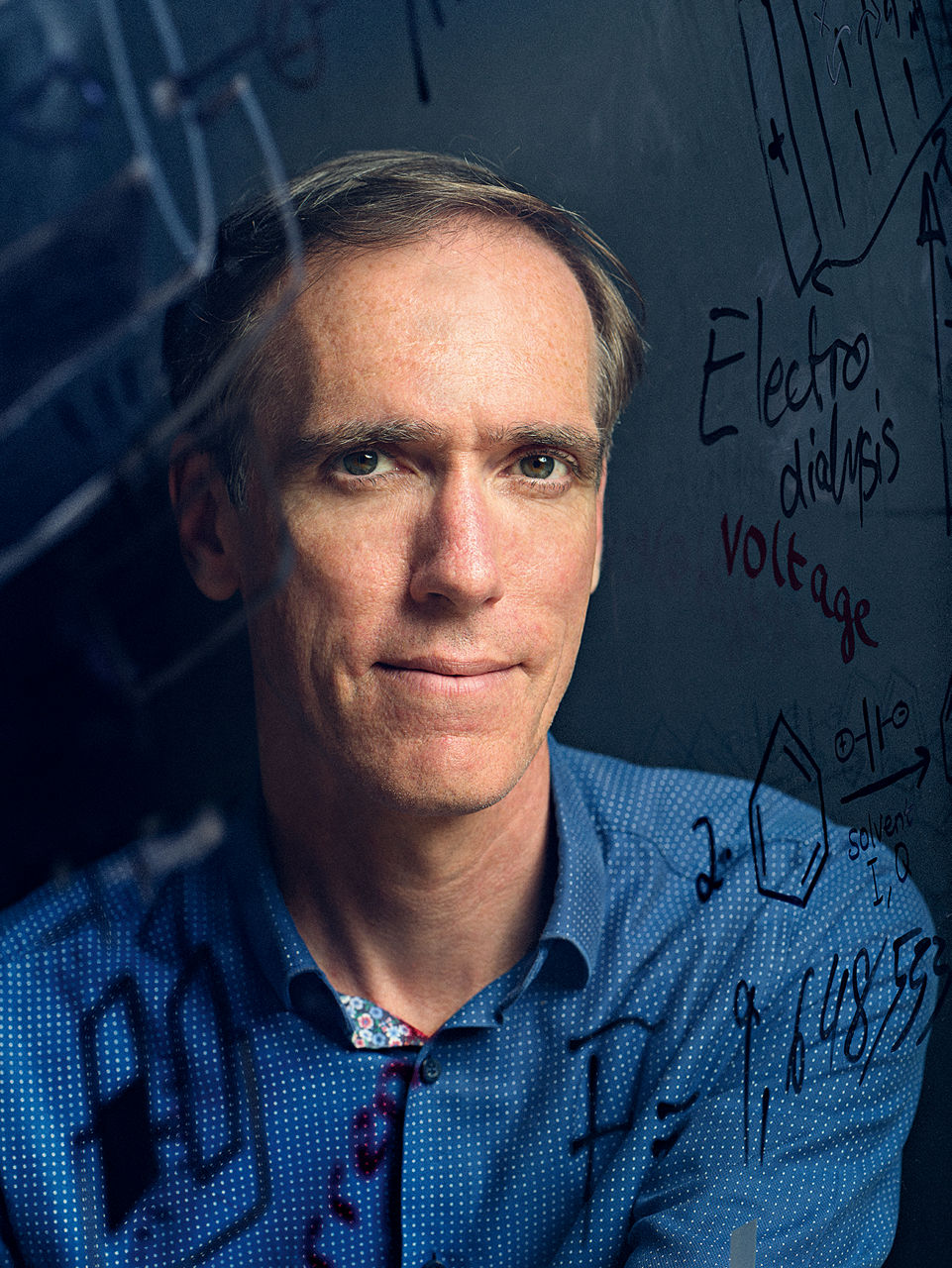 Ein Portrait von Patrik Stenner durch eine Glasscheibe mit zahlreihen Filzstiftnotizen darauf.