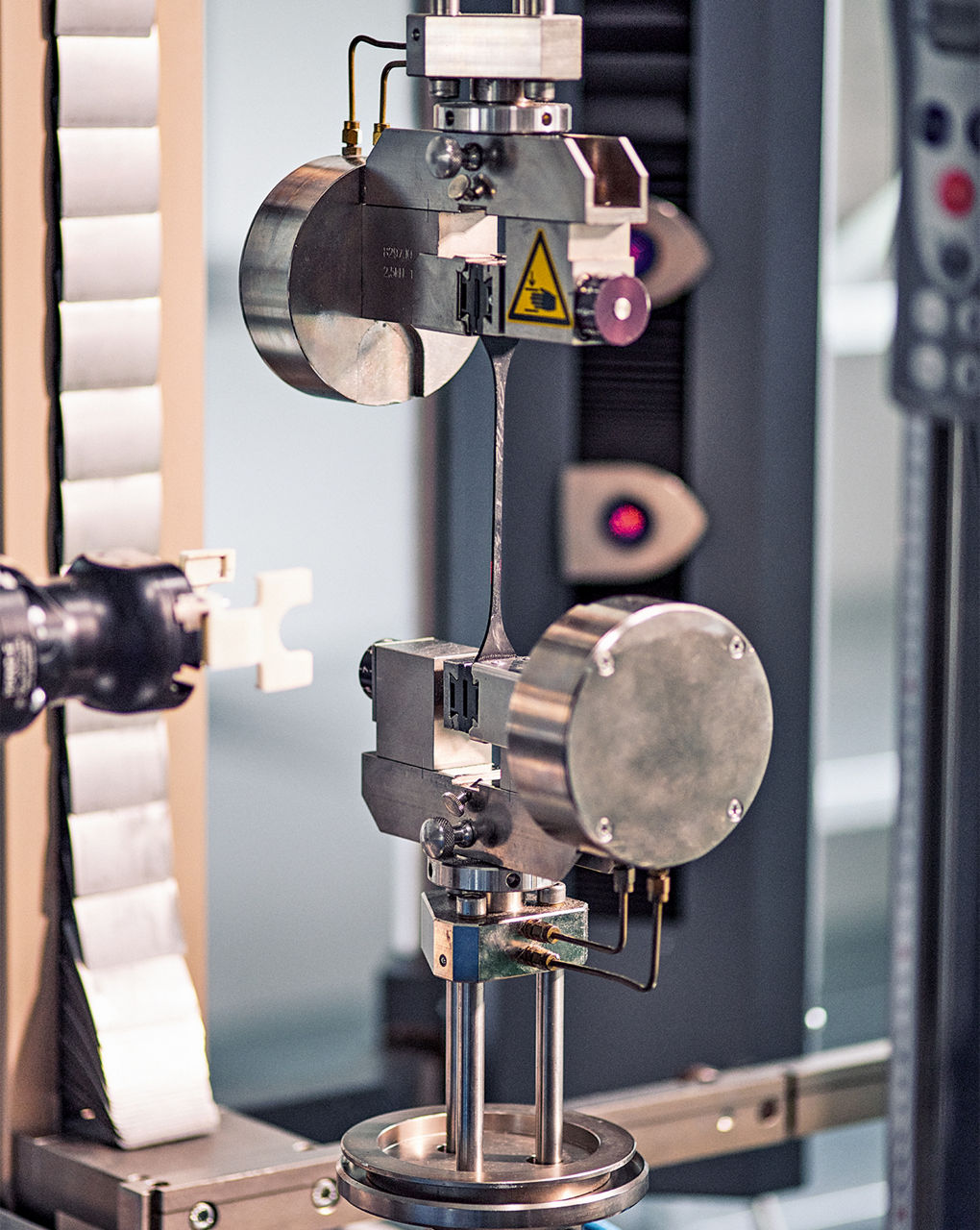 Ein Prüfgerät zieht an einem Prüfkörper, um die Reißfestigjeit zu testen.