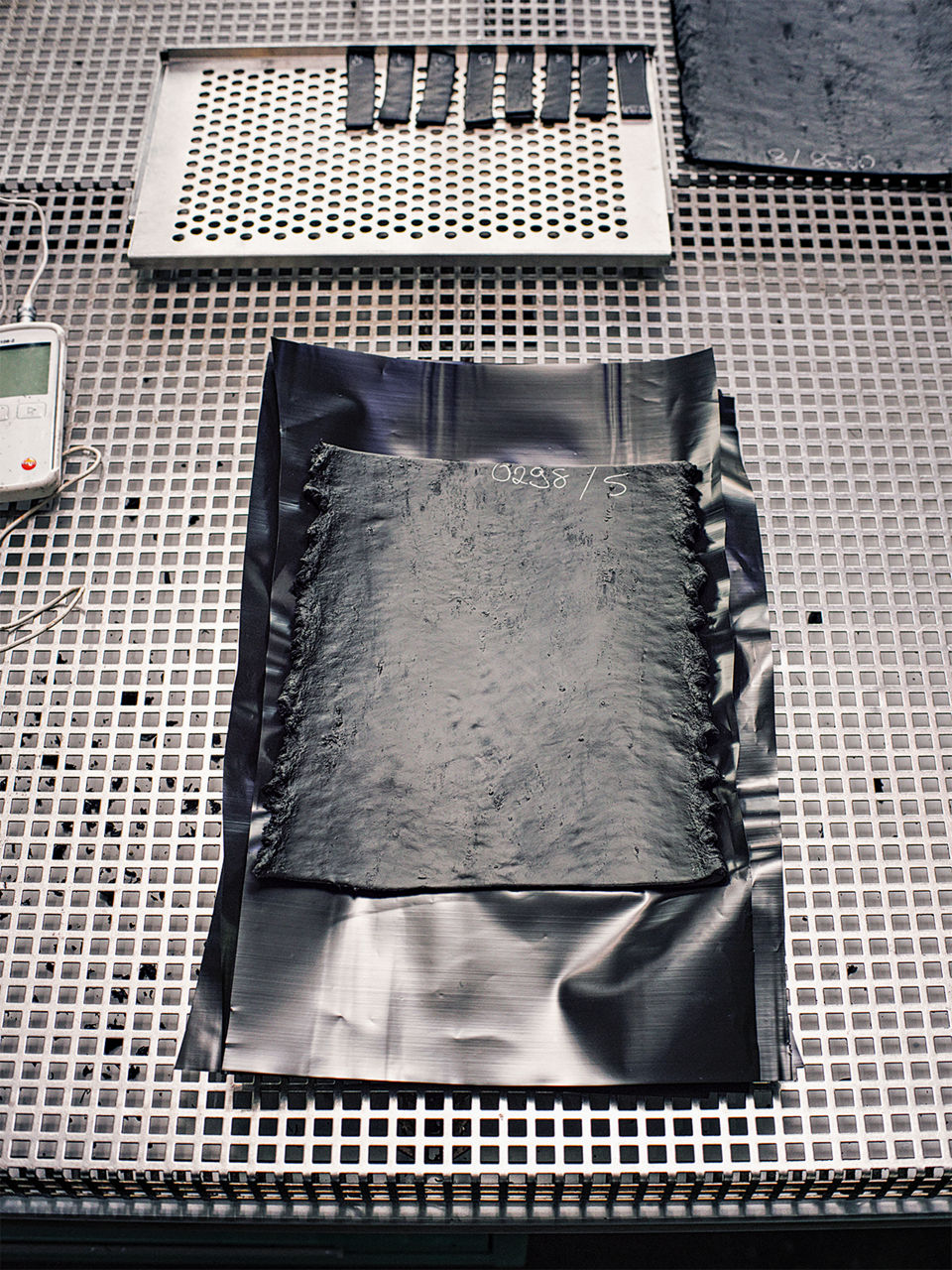 Ein rechteckiges Stück Gummi liegt auf einer gitterförmigen Unterlage.