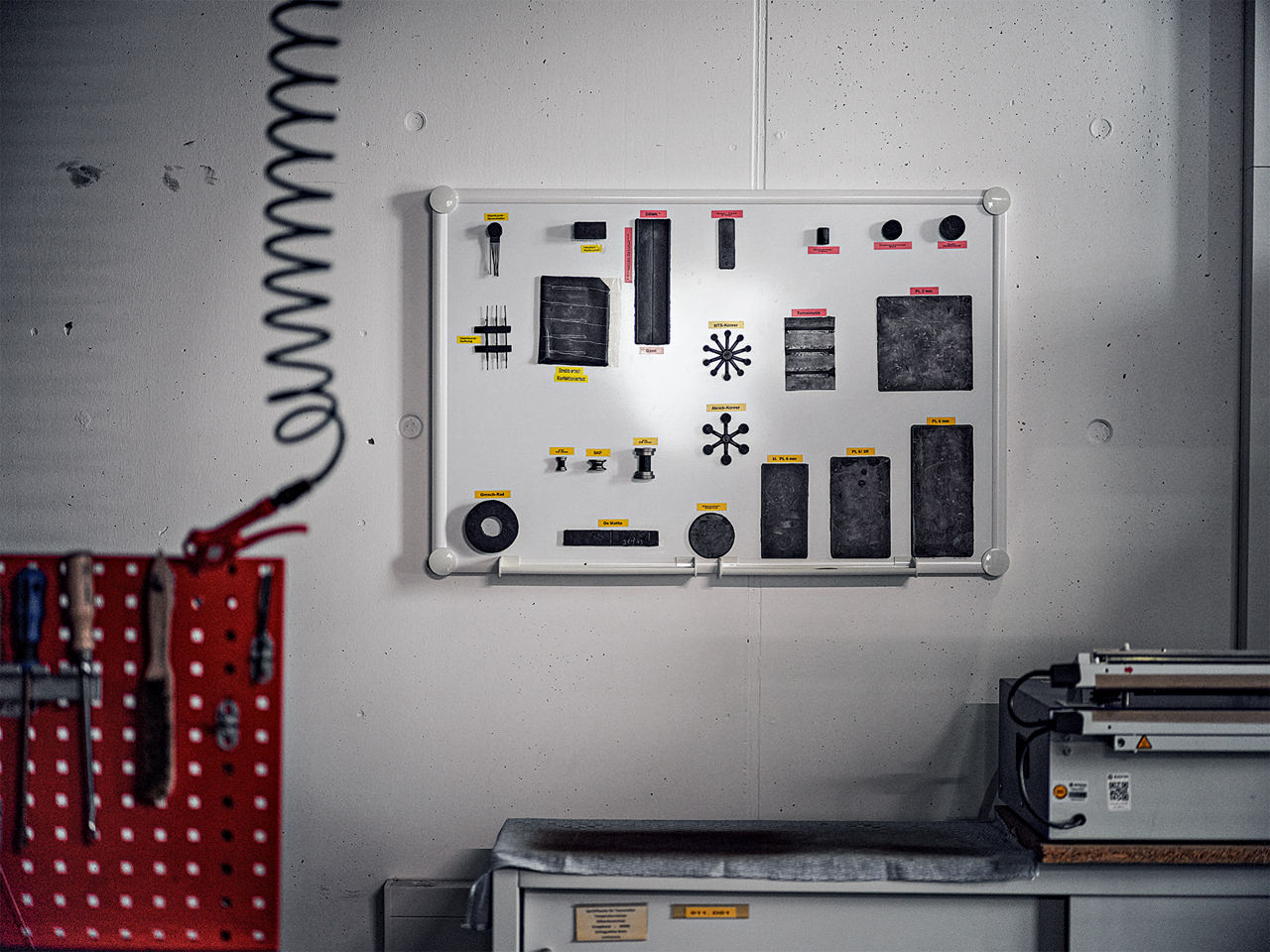 Verschiedene Gummi-Muster hängen an einem White-Board an einer Wand.